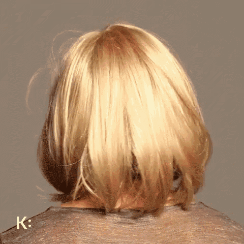the back of a woman 's head with blonde hair and the letter k on the bottom