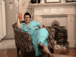 a woman in a blue dress sits in a chair holding a drink