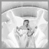 a black and white photo of a woman in a white dress standing in front of a fountain .
