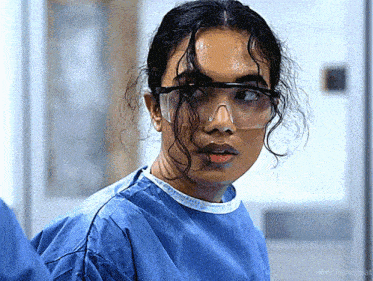 a close up of a woman wearing goggles and a blue gown