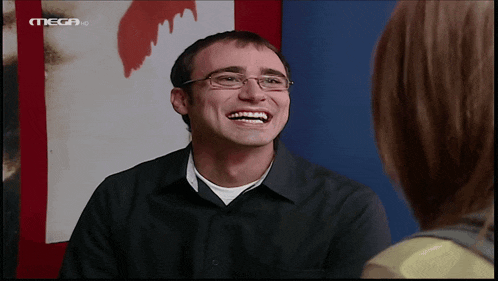 a man with glasses is smiling in front of a mega hd logo