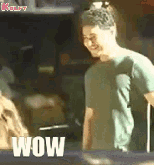 a man in a green shirt is standing next to a table with the word wow on it