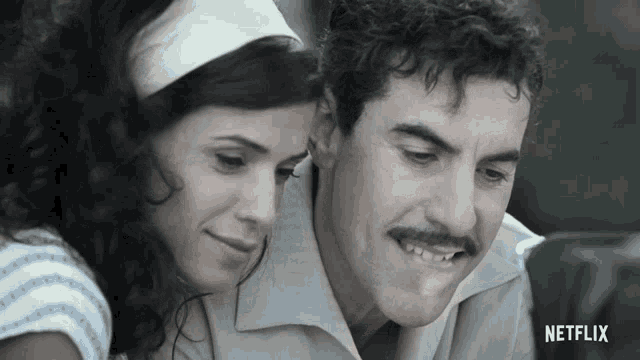 a man and a woman are looking at a screen with netflix written on the bottom