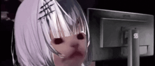 a girl with white hair and black eyes is sitting in front of a computer monitor .