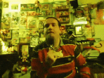 a man in a red and black striped shirt is standing in front of a wall full of posters