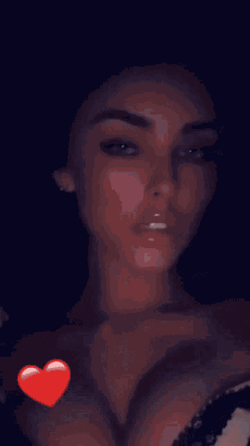 a close up of a woman 's face with a red heart on her chest .