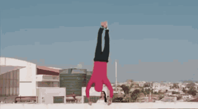 a man in a red shirt is doing a handstand in front of a woman in a white top .