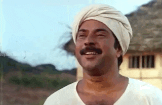 a man with a mustache wearing a turban and smiling .