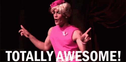 a man in a pink dress is standing on a stage with the words totally awesome behind him .