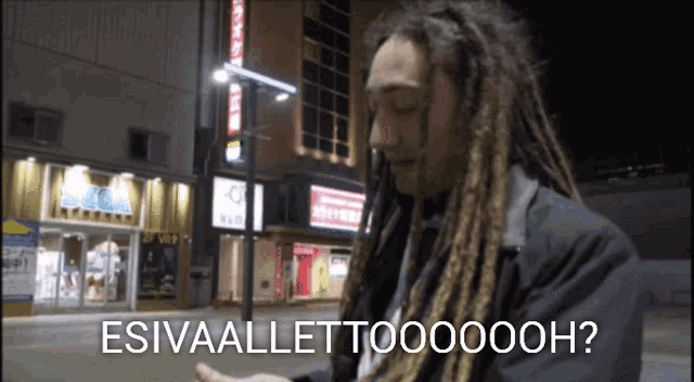 a man with dreadlocks stands in front of a building that says sega