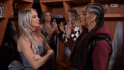 a group of women are standing in a locker room with a cw logo in the background