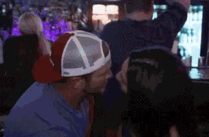 a man wearing a red hat is kissing another man