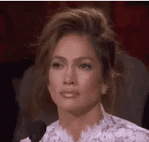 a woman in a white dress is sitting in front of a microphone and making a funny face .