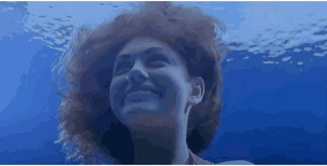 a woman is swimming underwater and smiling
