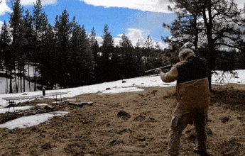 a man is standing in a field with a shotgun