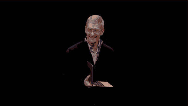 a group of people sitting in a dark room applauding and smiling