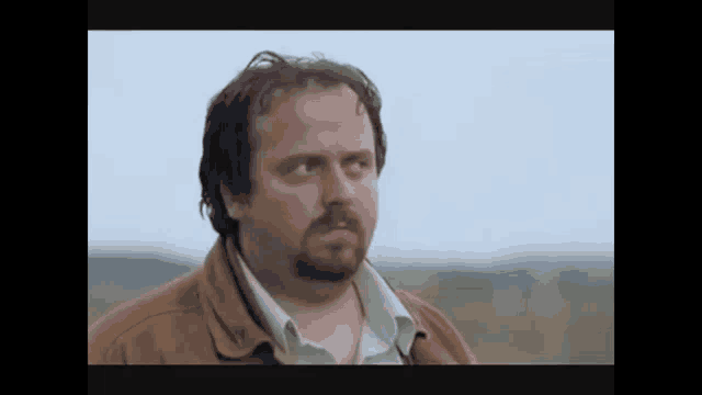 a man with a beard wearing a brown jacket