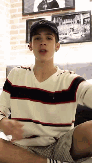 a young man wearing a hat and a striped shirt