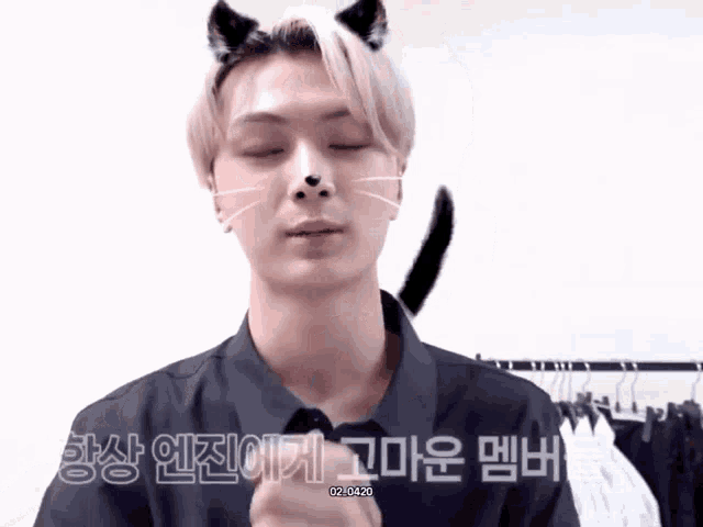 a young man with a cat ear on his head looks at the camera with his eyes closed