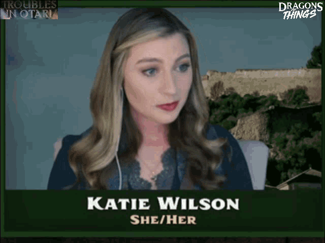 a woman named katie wilson sits in front of a dragons things sign