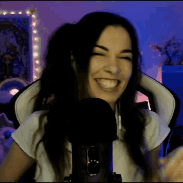 a woman is smiling while sitting in front of a microphone