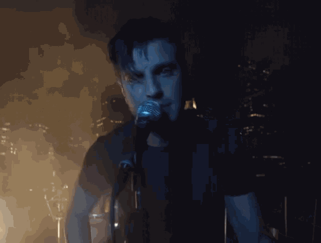 a man singing into a microphone with a city in the background