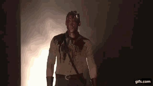 a man with blood on his face is standing in the dark .