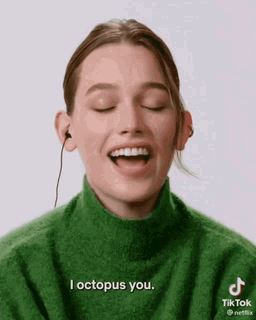 a woman in a green sweater says " i octopus you " while wearing headphones