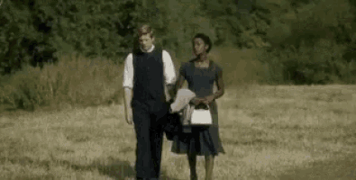 a man and a woman are walking across a field .