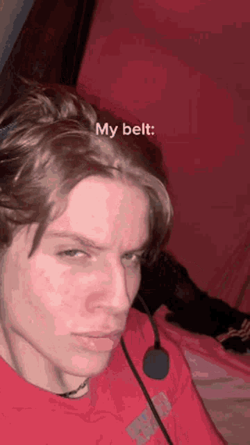 a young man is wearing a red shirt and a headset with the words my belt written on his face .