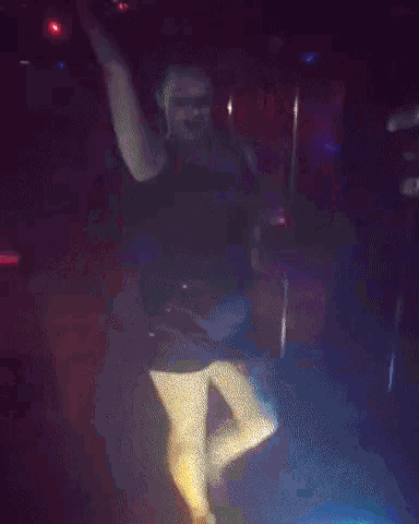a woman dancing in a dark room with purple lights