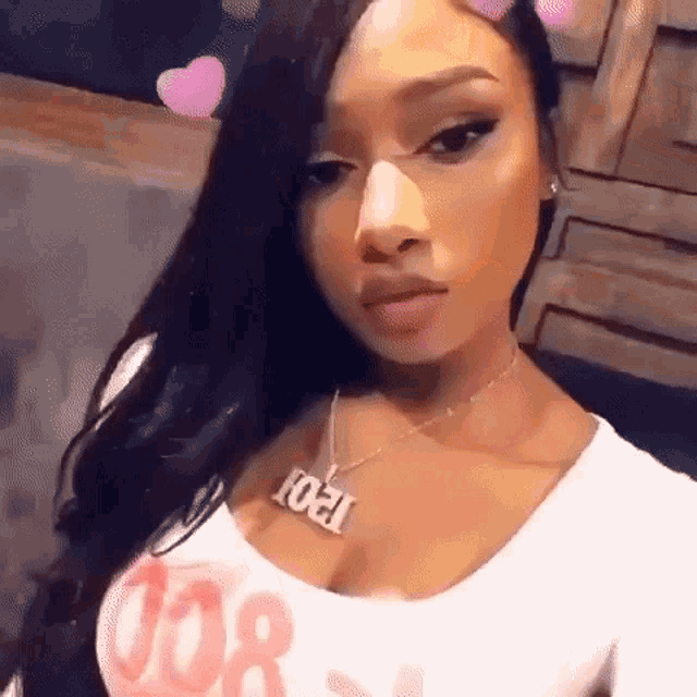 a close up of a woman wearing a necklace and a white top .