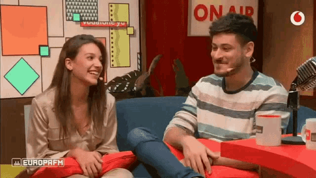 a man and a woman are sitting in front of a sign that says onair