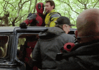 a man in a superhero costume is standing on top of a car