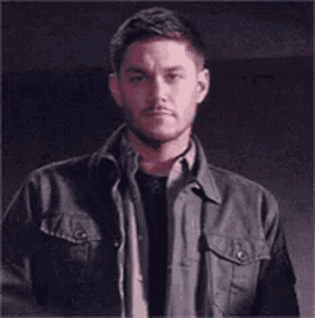 a man in a leather jacket is making a gesture with his hands .