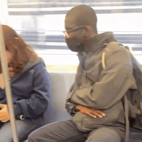 a man wearing a mask is sitting on a train