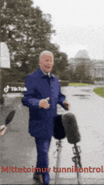 a man in a blue suit is walking down a street with a microphone in front of him and a tiktok logo behind him