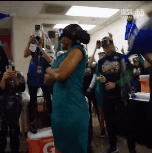 a woman in a green dress is dancing in front of a cooler that says gatorade