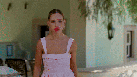 a woman in a white dress with red lips is standing in front of a building