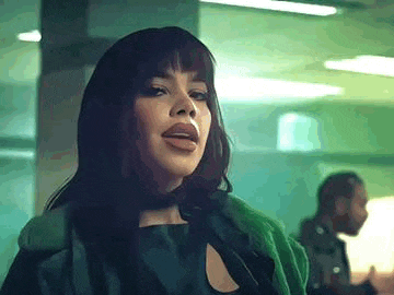 a woman in a green coat is standing next to a man in a dark room .