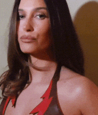 a close up of a woman 's face with a red lightning bolt on her chest .