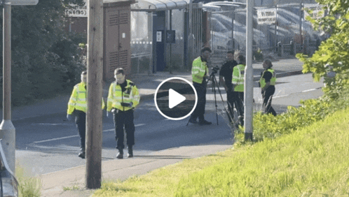 a group of police officers walking down a street with a play button