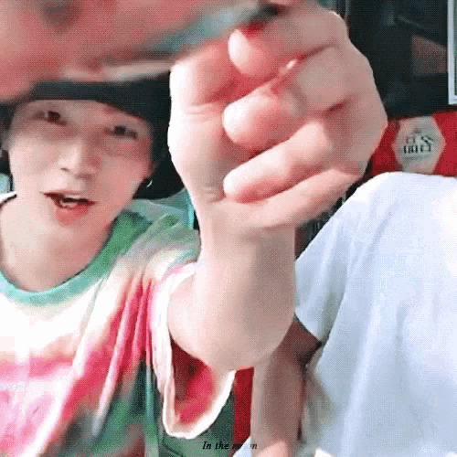 a close up of a person 's hand pointing at the camera while wearing a tie dye shirt .