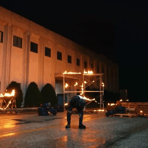 a man is bending over in front of a building with flames coming out of the scaffolding