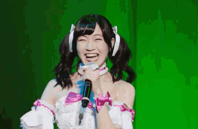 a girl with pigtails is holding a microphone in front of a green background