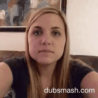 a woman is sitting on a couch and making a funny face in front of a painting .