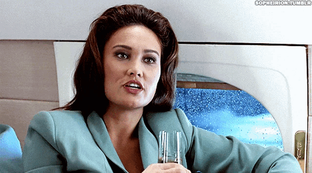 a woman in a blue suit is holding a glass in her hand