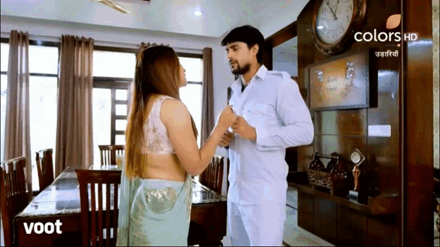 a man and a woman are standing in front of a clock on a screen that says colors hd