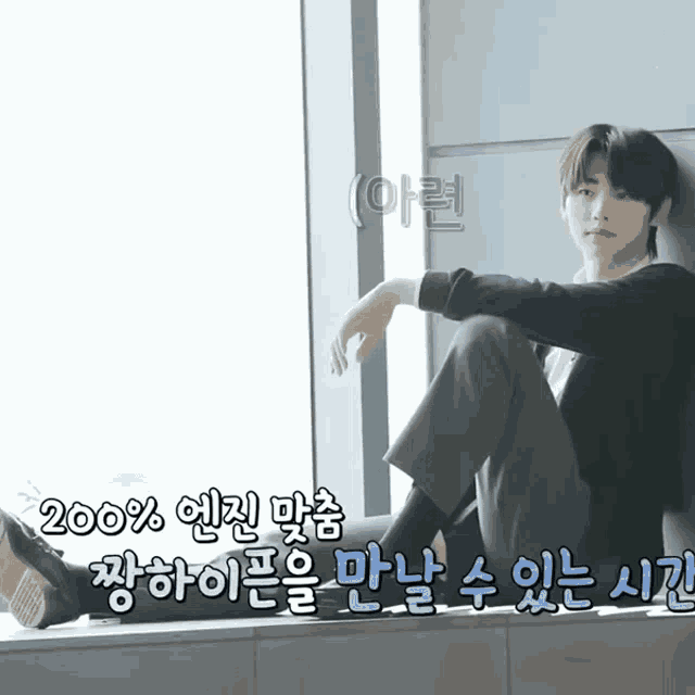 a young man sits on a window sill with korean writing on the bottom