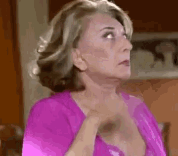 a woman in a pink shirt is looking up at something .